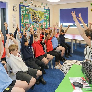 athro a myfyrwyr gyda'u dwylo i fyny