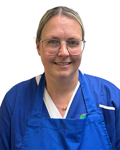 Staff y Gegin Gemma Smith yn gwisgo sbectol a gwisg gegin las
